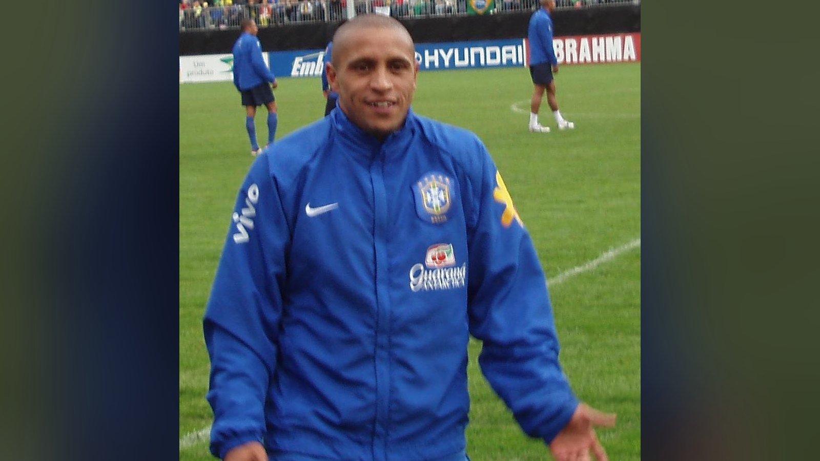 Roberto Carlos de agasalho azul da selecao brasileira, sorrindo em campo durante treino em 2006