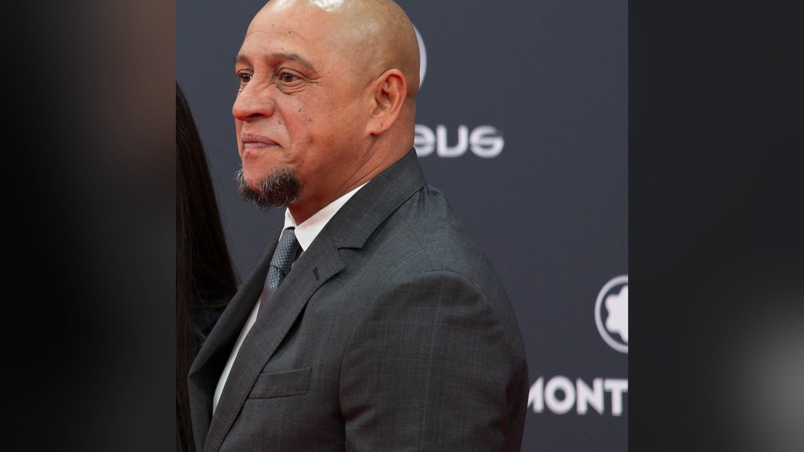 Roberto Carlos de terno cinza e gravata, de perfil, no tapete vermelho do Laureus de 2024
