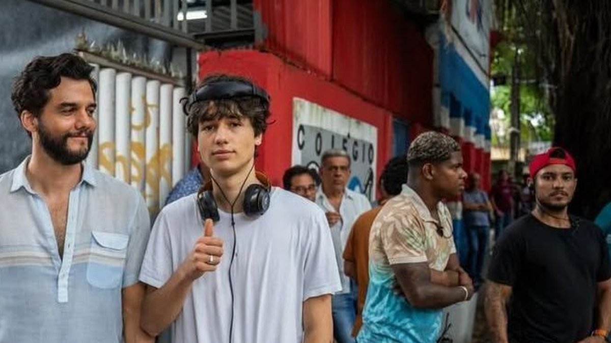 Wagner Moura ao lado de um jovem em locação de filmagem.