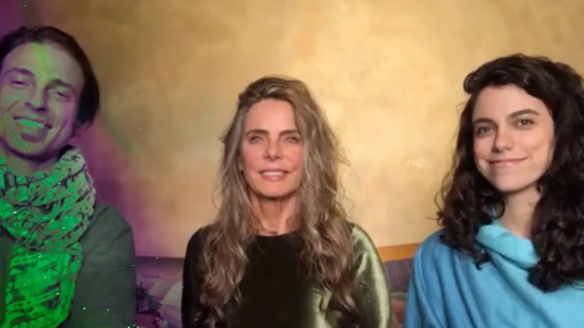 Kim Riccelli, de cachecol verde, Bruna Lombardi e Carla Labate, de cabelo cacheado, sentados lado a lado numa live