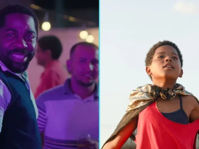 Lázaro Ramos sorri em cena de festa de Feito Pipa, ao lado de Yuri Gomes, o protagonista Gugu, com uma capa nos ombros